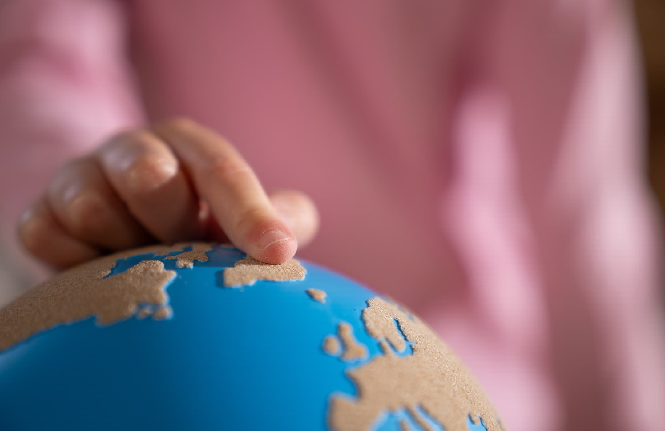 A close-up of a child's finger touching a rough-smooth globe from Nienhuis.